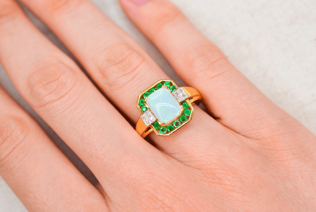 bague-en-or-jaune-ornee-d-une-opale-rectangulaire-entouree-d-emeraudes-rondes-en-serti-rail-et-de-diamants-ronds-bague-mariage