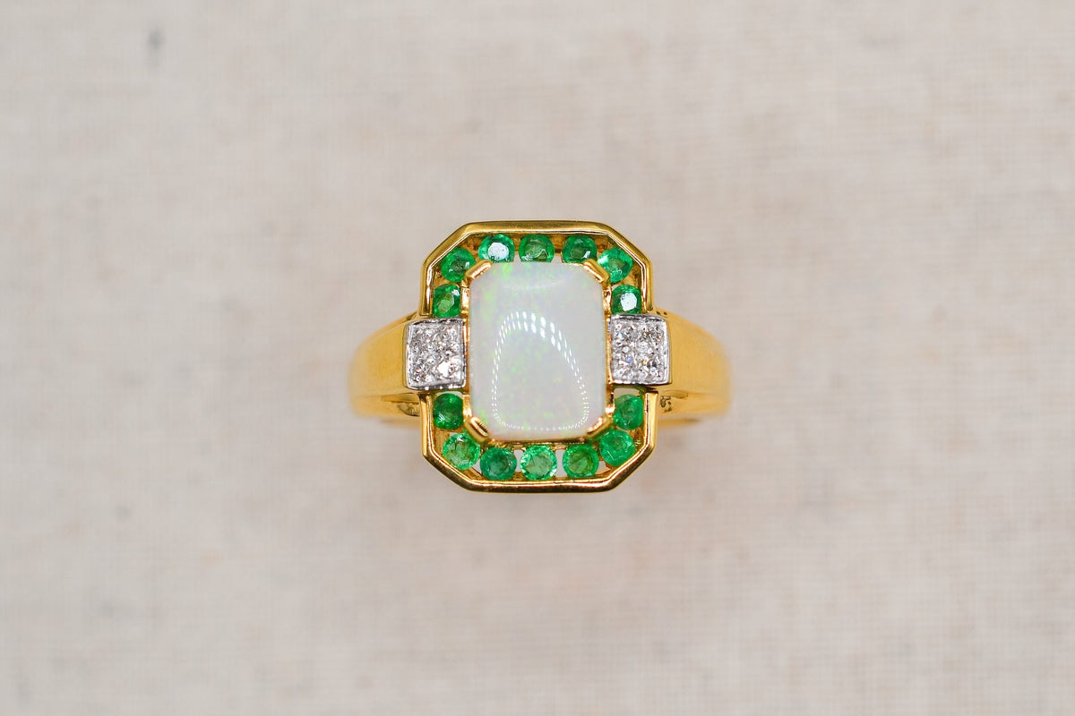 bague-en-or-jaune-ornee-d-une-opale-rectangulaire-entouree-d-emeraudes-rondes-en-serti-rail-et-de-diamants-ronds-bague-de-fiancailles