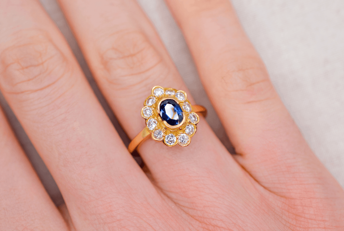 bague-marguerite-en-or-jaune-ornee-d-un-saphir-dans-un-entourage-de-12-diamants-bague-romantique