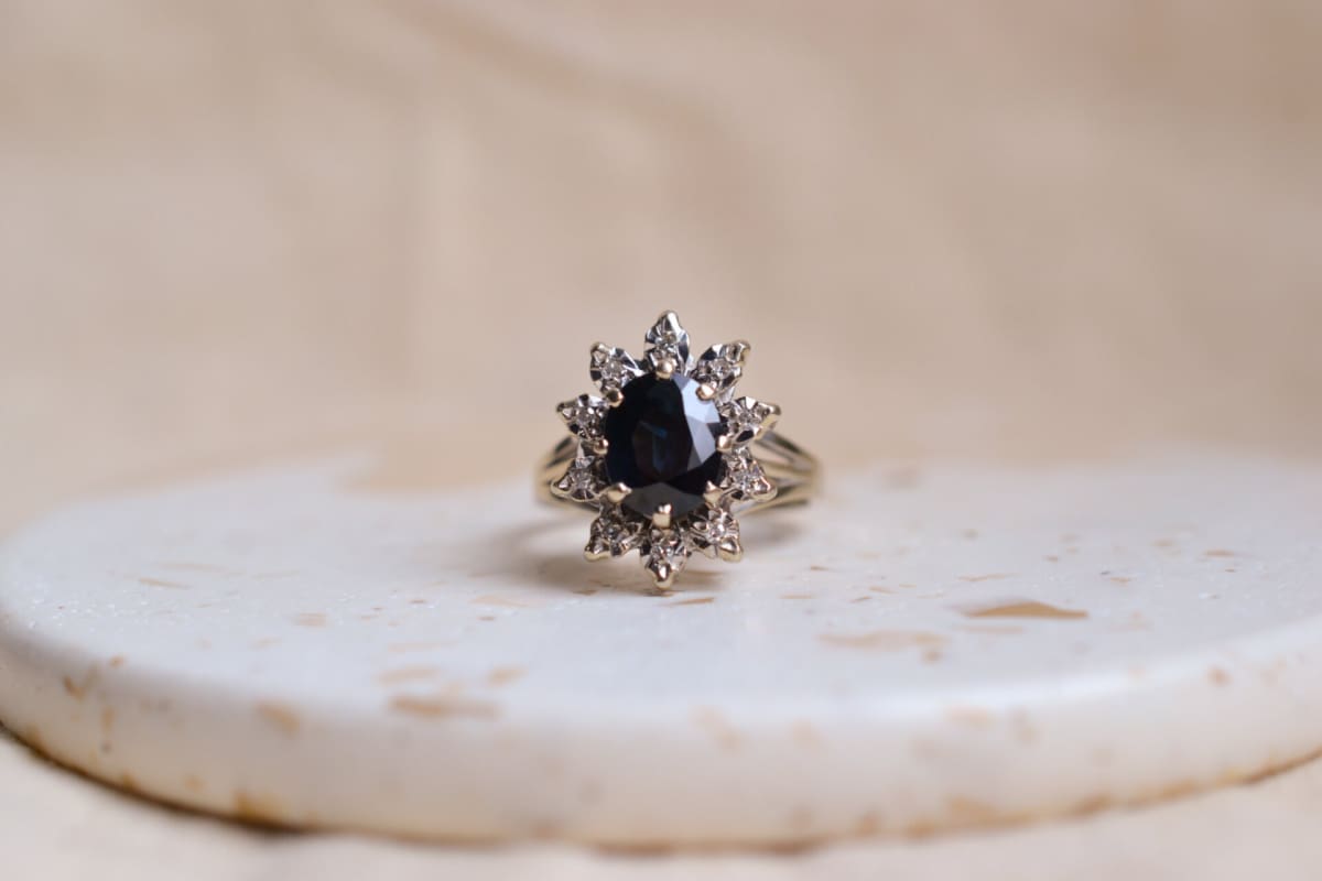 Bague Marguerite en Or blanc 18 carats sertie griffes d'un Saphir taille ovale dans un entourage de Diamants