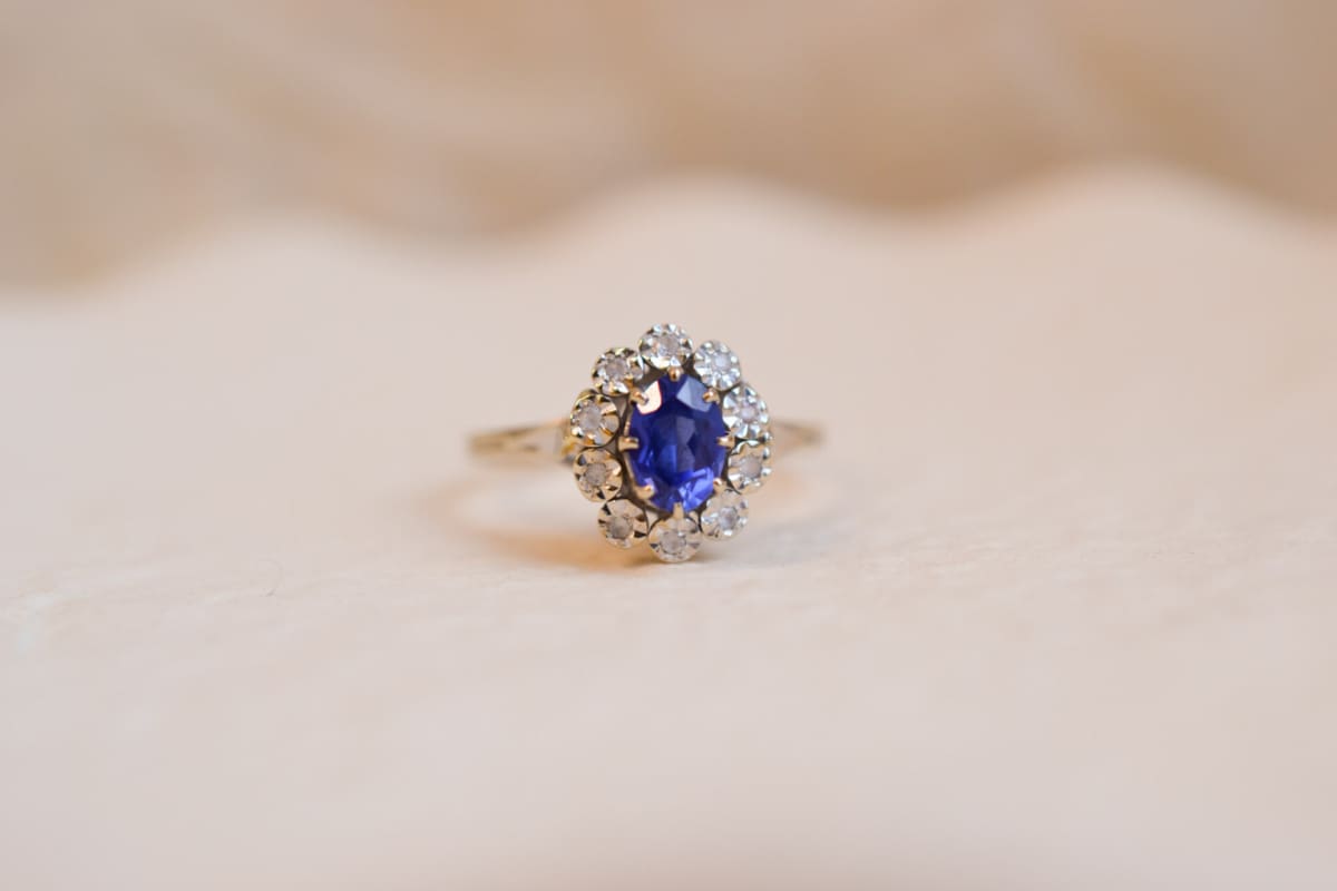 Bague Marguerite ancienne en Or blanc 18 carats centrée d'une pierre bleue entourée de pierres blanches