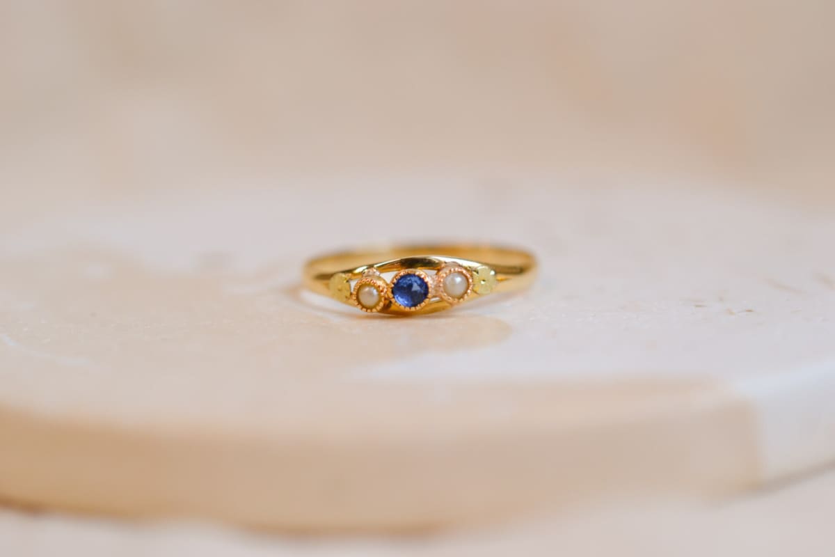 Bague ancienne en Or jaune 18 carats centrée d'un Saphir de synthèse épaulé par 2 Perles