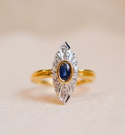 Bague Marquise en Or jaune 18 carats centrée d'un Saphir serti clos en Or jaune sur une illusion de pavage en Or blanc