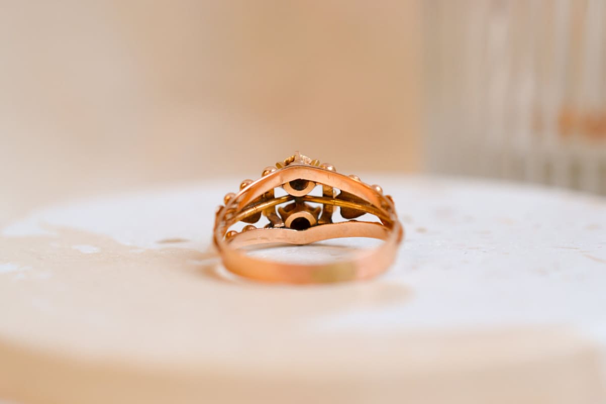 Bague ancienne en Or rose 18 carats ornée de Perles dans un décor de fleur épaulées par des noeuds dans un entourage de billes d'Or