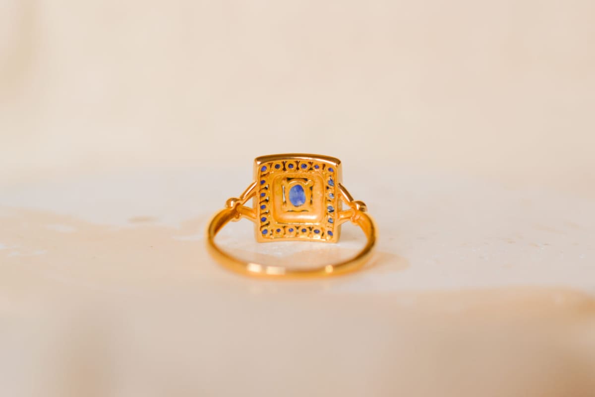 Bague carrée en Or jaune 18 carats centrée d'un Saphir sur un pavage d'Or blanc entouré de Saphirs