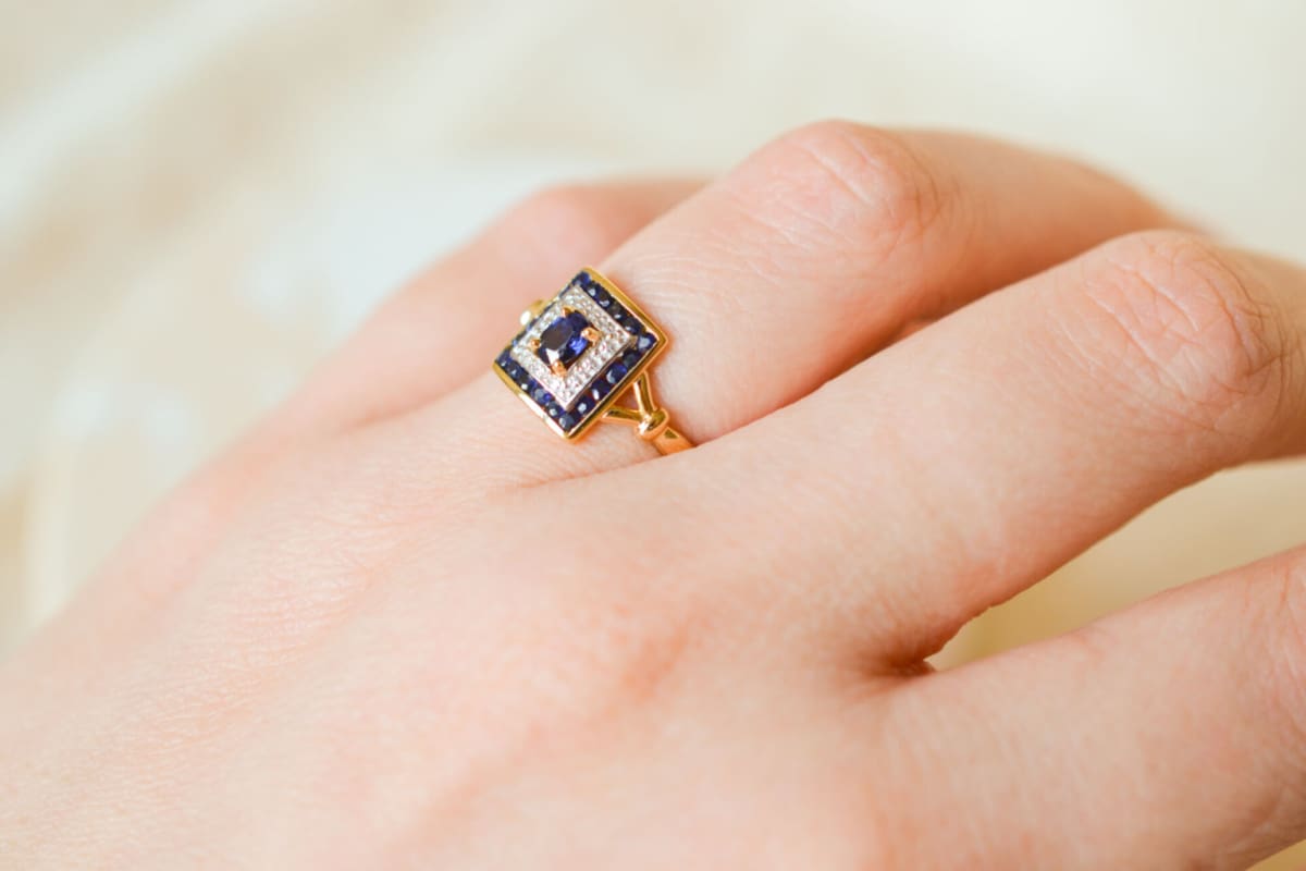 Bague de fiançailles Vintage en Or jaune 18 carats sertie d'un Saphir sur un pavage d'Or blanc entouré de Saphirs calibrés