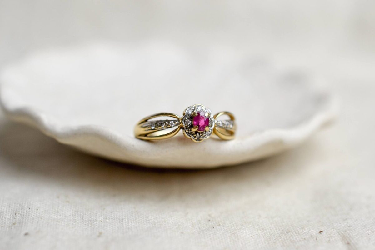 bague en or jaune surmontee d un rubis de taille ovale dans un entourage de petits diamants - bague vintage