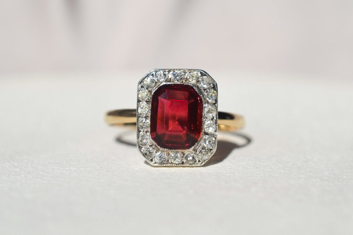 Bague octogonale en or jaune sur le corps de bague et or blanc pour la tête de bague. Tête de bague carrée ornée d'un halo d'oxydes et d'un carré central de verre rouge
